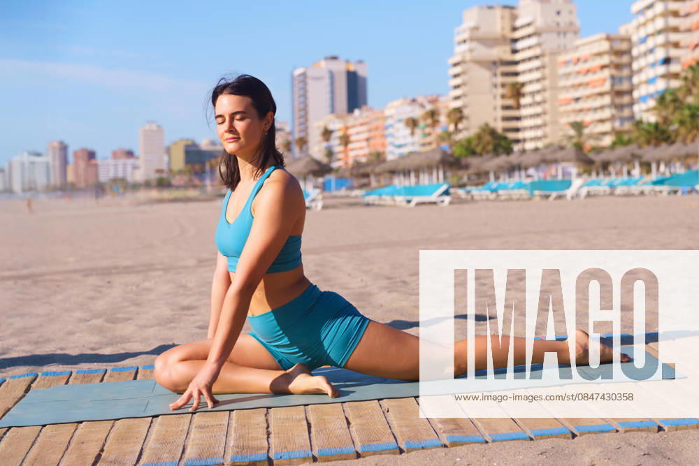 MR_ID32617_23682_RenataRusso.jpg A woman practices yoga on a calm, sandy beach with gentle waves in the distance. Her tranquil pose and peaceful surroundings highlight the serenity and mindfulness of yoga. Model Released Jultud_ID32617_1111241_051
