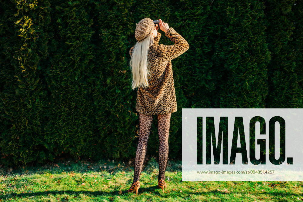 Stylish person in leopard jacket taking photographs in garden outdoors model released, Symbolfoto, VSNF04572
