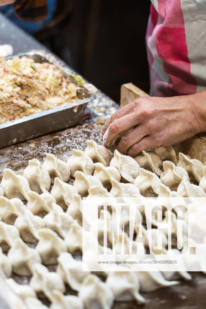 IMAGO Creative, Food, Dumplings Skilled hands crafting fresh dumplings in Taiwan kitchen A close-up of hands expertly folding fresh dumplings on a floured surface in a traditional kitchen setting in Taiwan, highlighting authentic Asian culinary craftsmanship. Model Released JavierBallester_ID33758_1188670_006
