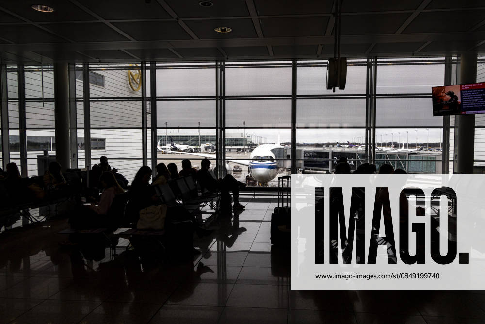 Silhouettes Of Passengers Waiting At An Airport Terminal Silhouettes of international passengers walking with luggage and bags while others are sitting and waiting at a modern airport terminal next to the passenger boarding gates with an Airbus A350 aircraft of Air China visible behind them at the apron of Munich Airport MUC, or Flughafen München, named after the former Bavarian minister-president Franz Josef Strauss, the second busiest airport in Germany hub for the German airline Lufthansa. Munich, Germany on February 22, 2026 Munich Germany