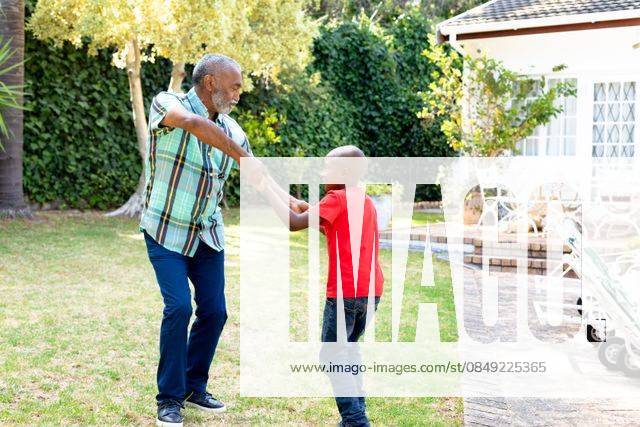 Senior African American man and his grandson spending time together in their garden on a sunny day Senior African American man spending time with his grandson in their garden on a sunny day, teaching him dancing on the lawn., model released, , property released, Cape Town, South Africa, 24.01.2020, 1352259.jpg, people,real people,home,domestic life,lifestyle,free time,leisure,relaxing,happy,enjoying,smiling,summer,garden,backyard,sunny,hobby,heathy,nature,heathy lifestyle,active seniors,retirement,interacting,togetherness,closeness,grandfather,grandson,teaching,learning,dancing,playing,fun Child,Boy,Male,Black,Senior,Elderly,Man,Mixed-Race Outdoors,Side view,Focus on Foreground,Looking Away,Two objects,Day,Full length