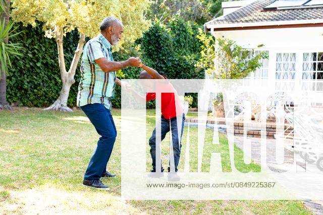 Senior African American man and his grandson spending time together in their garden on a sunny day Senior African American man spending time with his grandson in their garden on a sunny day, teaching him dancing on the lawn., model released, , property released, Cape Town, South Africa, 24.01.2020, 1352260.jpg, people,real people,home,domestic life,lifestyle,free time,leisure,relaxing,happy,enjoying,smiling,summer,garden,backyard,sunny,hobby,heathy,nature,heathy lifestyle,active seniors,retirement,interacting,togetherness,closeness,grandfather,grandson,teaching,learning,dancing,playing,fun Child,Boy,Male,Black,Senior,Elderly,Man,Mixed-Race Outdoors,Side view,Focus on Foreground,Looking Away,Two objects,Day,Full length