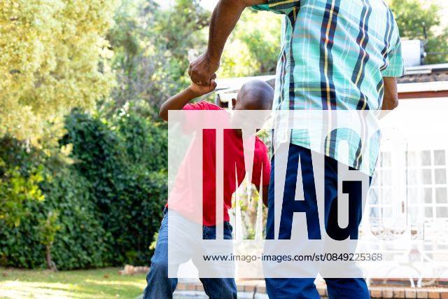 Senior African American man and his grandson spending time together in their garden on a sunny day Senior African American man spending time with his grandson in their garden on a sunny day, teaching him dancing on the lawn., model released, , property released, Cape Town, South Africa, 24.01.2020, 1352261.jpg, people,real people,home,domestic life,lifestyle,free time,leisure,relaxing,happy,enjoying,smiling,summer,garden,backyard,sunny,hobby,heathy,nature,heathy lifestyle,active seniors,retirement,interacting,togetherness,closeness,grandfather,grandson,teaching,learning,dancing,playing,fun Child,Boy,Male,Black,Senior,Elderly,Man,Mixed-Race Outdoors,Side view,Focus on Foreground,Looking Away,Two objects,Day,Three Quarter Length