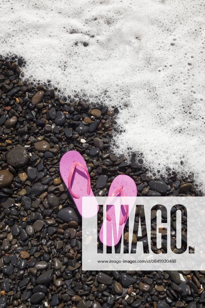 A pair of pink flip flops rest on wet rocks as a foamy ocean wave approaches the shore in Florence, Oregon. Footwear,United States,A pair of pink flip flops rest on wet rocks as a foamy ocean wave approaches the shore in Florence, Oregon. A pair of pink flip flops rest on wet rocks as a foamy ocean wave approaches the shore in Florence, Oregon.