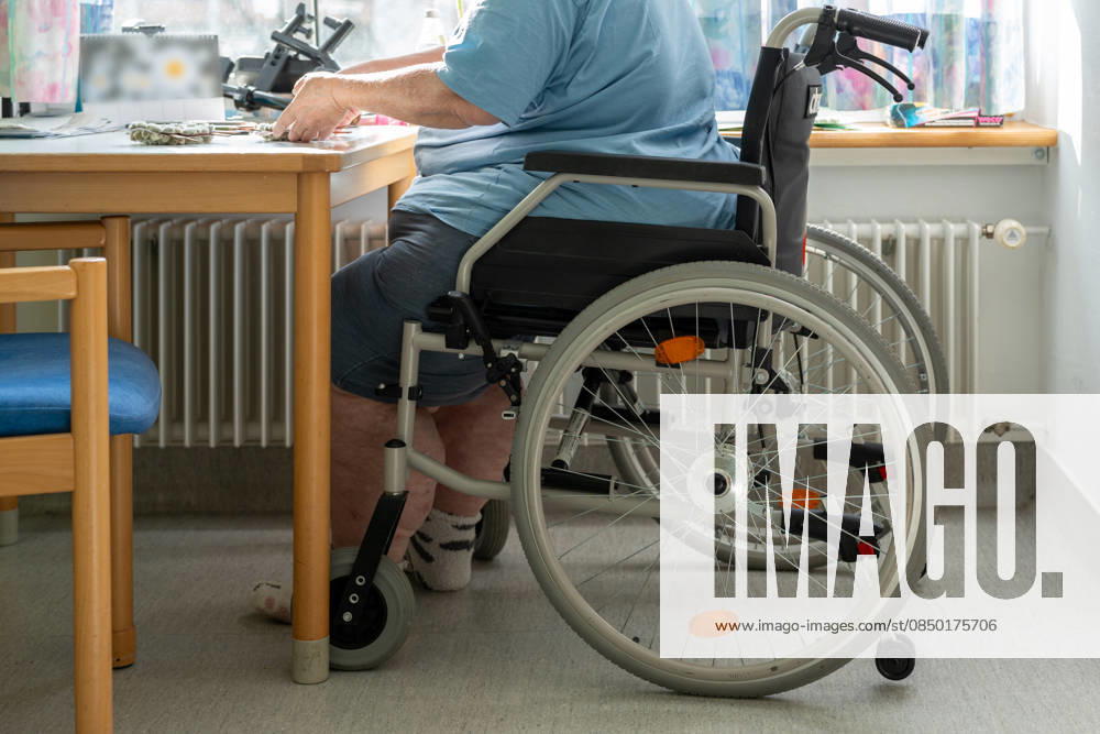 Ein älterer Mensch im Rollstuhl am Tisch verdeutlicht die Herausforderungen im Pflegealltag. Das Bild thematisiert Inklusion, Barrierefreiheit und die notwendige Unterstützung für ein würdevolles Leben.