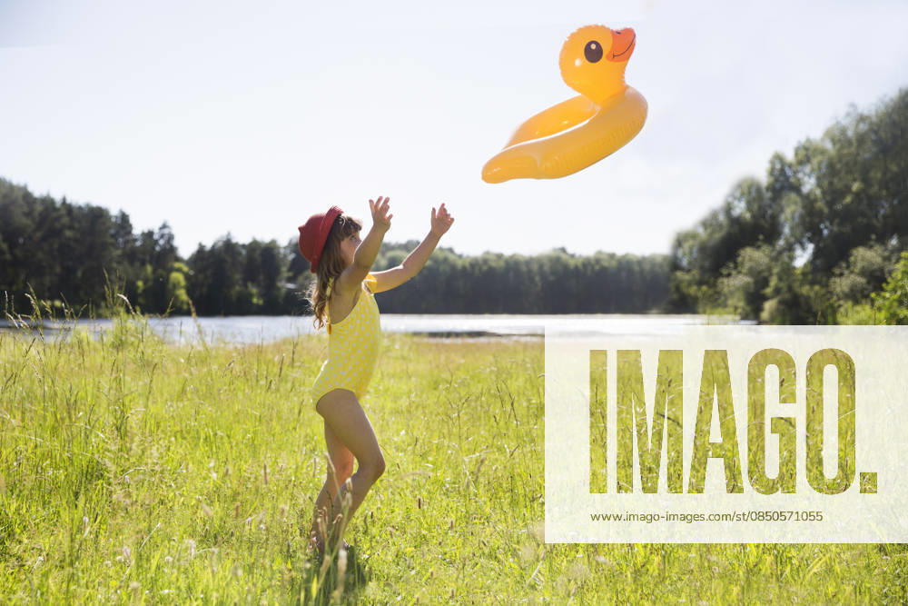 Mädchen im Badeanzug mit aufblasbarem Entenring geht an einem Sommertag im See schwimmen. Sommerferien in der Natur child girl in swimming suit with Duck shaped inflatable ring goes to swim on the lake during the summer day. summer holidays in nature (License=RF) ,model released, Symbolfoto