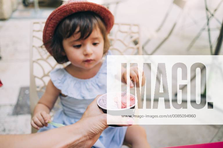 Cute toddler girl eating an ice cream held by her mother model released Symbolfoto GEMF02115