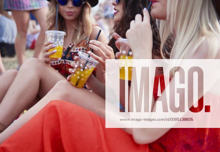 Friends drinking juice and sitting on meadow during music festival model released Symbolfoto ABIF00597