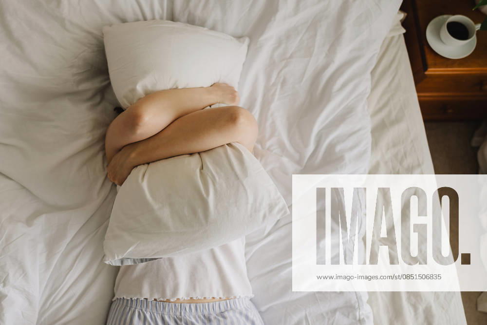 Fatigued woman hugging pillow in bed during a stressful morning model released, Symbolfoto property released, IGEF00811
