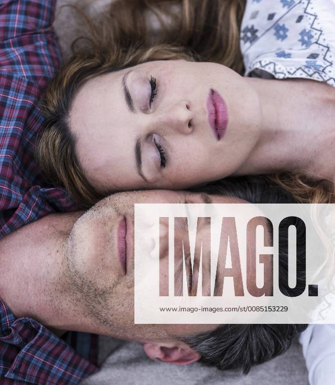 Couple with closed eyes lying down head to head model released Symbolfoto UUF14532
