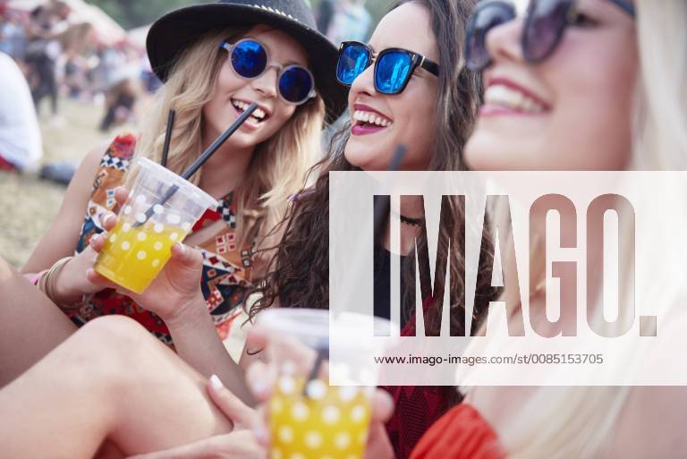 Friends drinking juice and sitting on meadow during music festival model released Symbolfoto ABIF00598