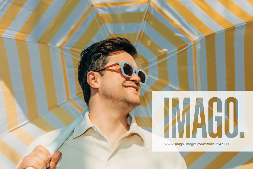 Smiling man with sunglasses under striped summer umbrella outdoors model released, Symbolfoto, VSNF04728
