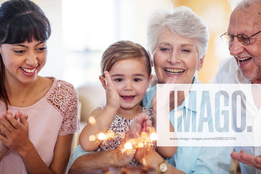 Little girl lwatching sparklers on a birthday cake, sitting on grandmother s lap model released Symbolfoto property released ZEF14250