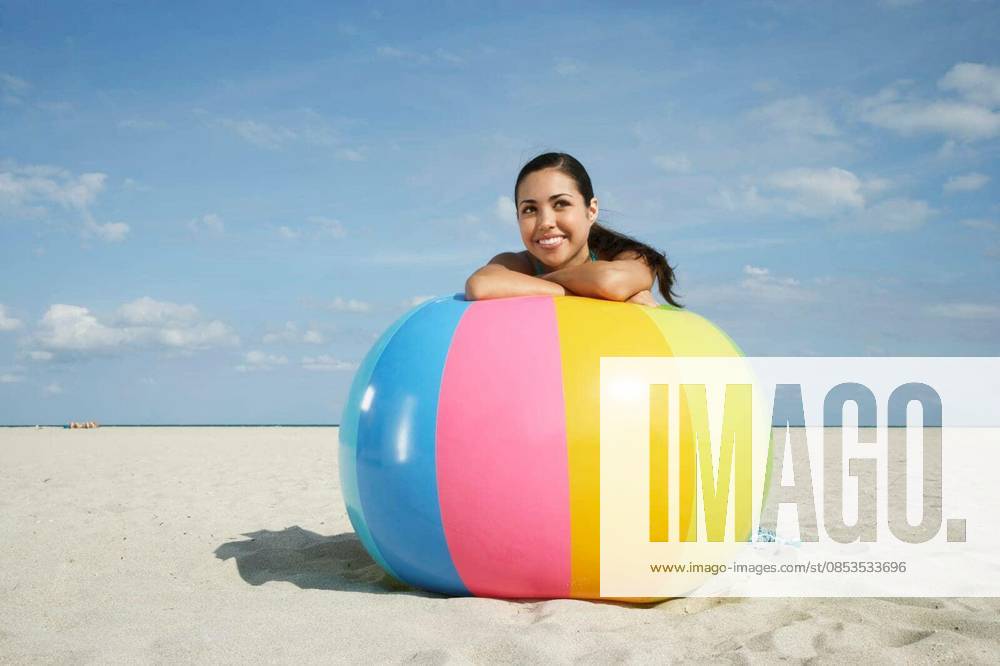 Teenage Girl Relaxing On Colorful Beach Ball - Happy teenage girl relaxing on large colorful ball on sandy beach model released Symbolfoto