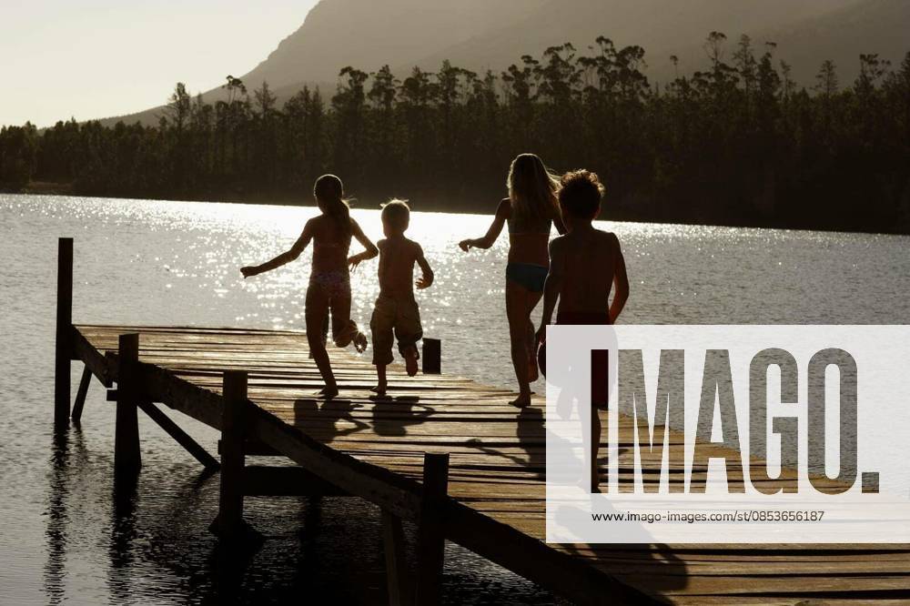 Children Running On Jetty At Lake - Rear view of young boys and girls running on jetty at lake model released Symbolfoto