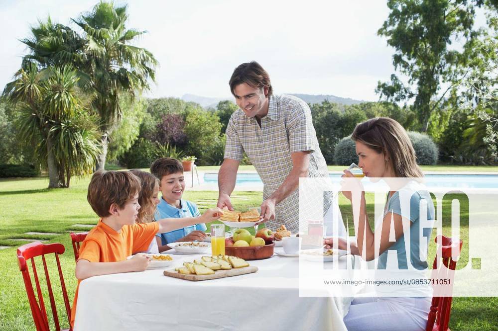 Family Sitting At Outdoor Breakfast Table - Couple with three children sitting at breakfast table outdoors model released Symbolfoto
