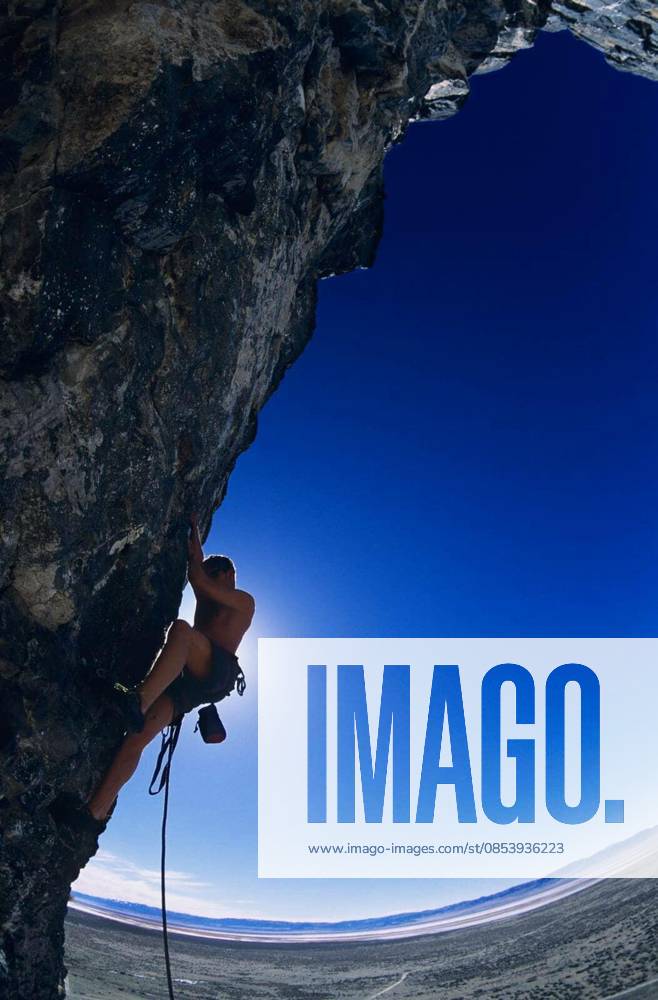 Rock Climber On Cliff Face - Side view of rock climber climbing up a cliff against clear blue sky model released Symbolfoto
