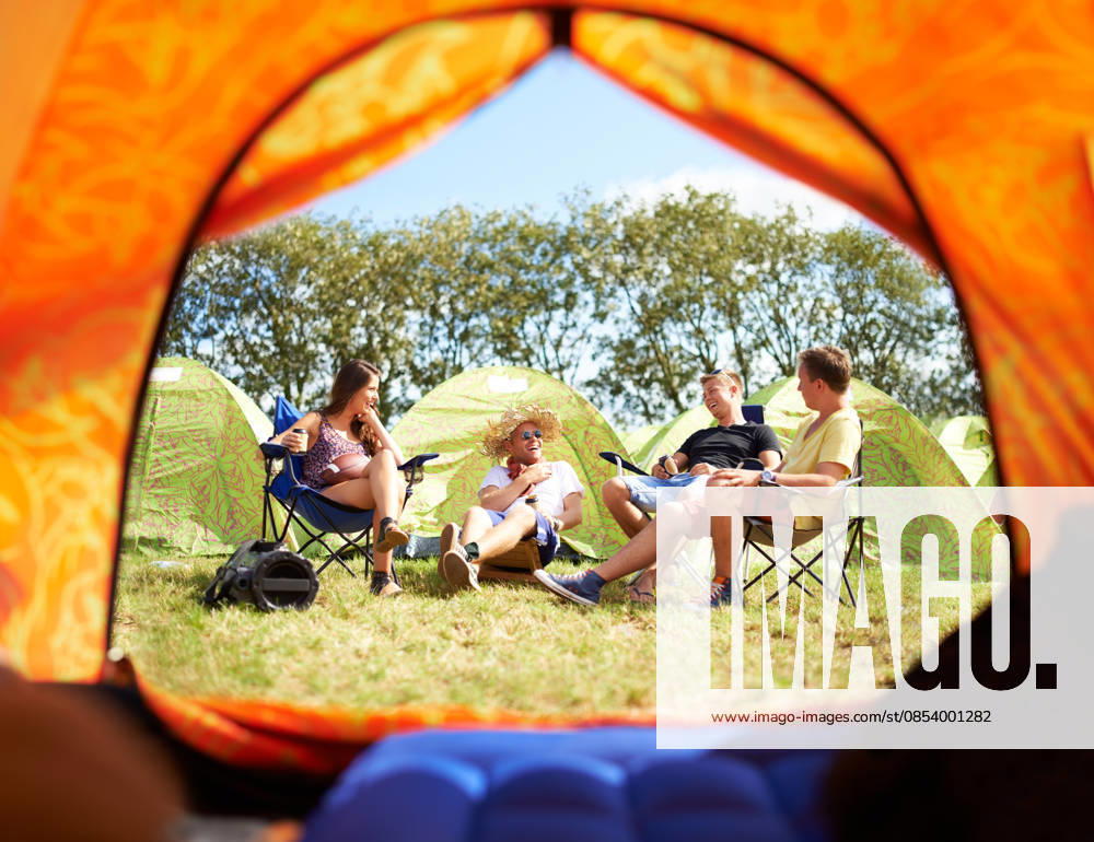 Shot of a group of friends sitting outside their tent at a festival. (License=RF) ,model released, Symbolfoto