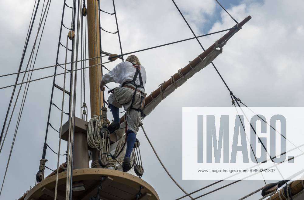 Seemann auf dem Aussichtsplattform, nachdem er die Takelage eines nachgebauten Segelschiffs erklommen hat, das nach Amerika segelte Sailor on lookout deck after climbing the rigging of replica sailing ship that sailed to America