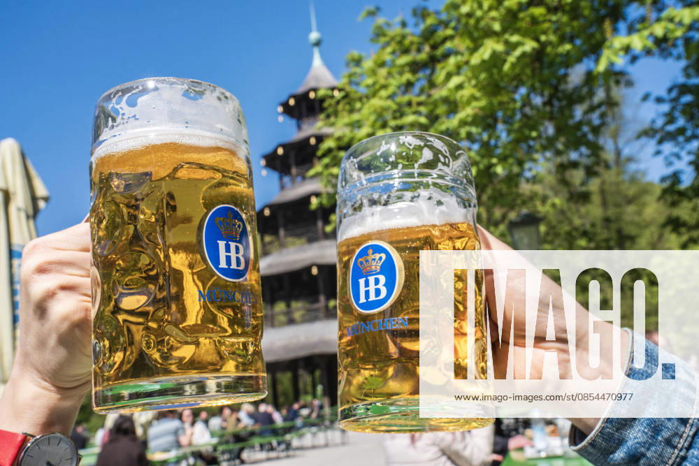 Biergarten am Chinesischen Turm, Frühlingstag im Englischen Garten, zwei Gäste stoßen mit ihrer Mass Bier an, München, April 2026 Deutschland, München, 22. April 2026, Biergarten am Chinesischen Turm, Frühling im Englischen Garten, Temperaturen bis 16 Grad, viele genießen die Sonne bei Bier und einer Brotzeit, zwei Gäste staßen mit ihren Masskrügen an, alles ist grün, Mittwochmittag, Bayern