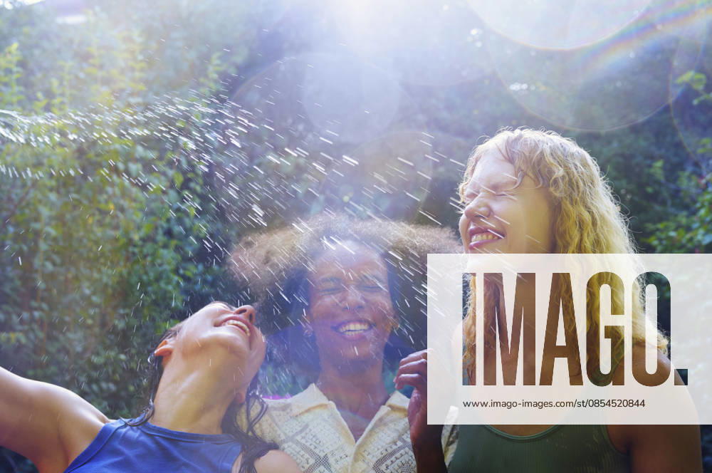 IMAGO Creative, Jahreszeit Sommer, Regen, Sommerregen Happy people enjoying water splash outdoors on a bright summer day model released, Symbolfoto, AZF00935