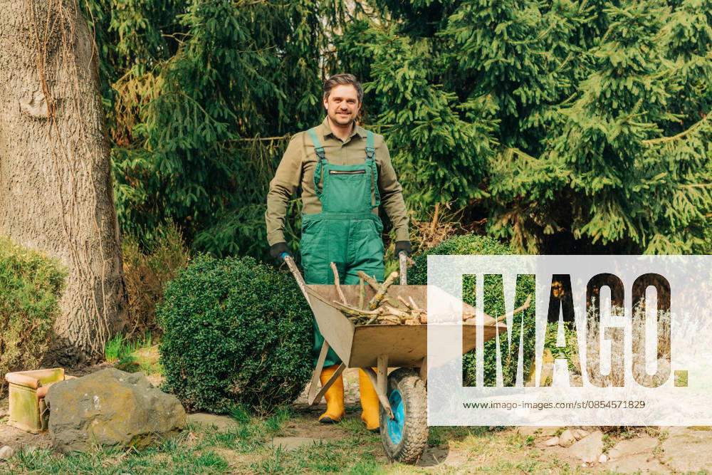 Smiling gardener with wheelbarrow pruning branches in spring model released, Symbolfoto, VSNF04779