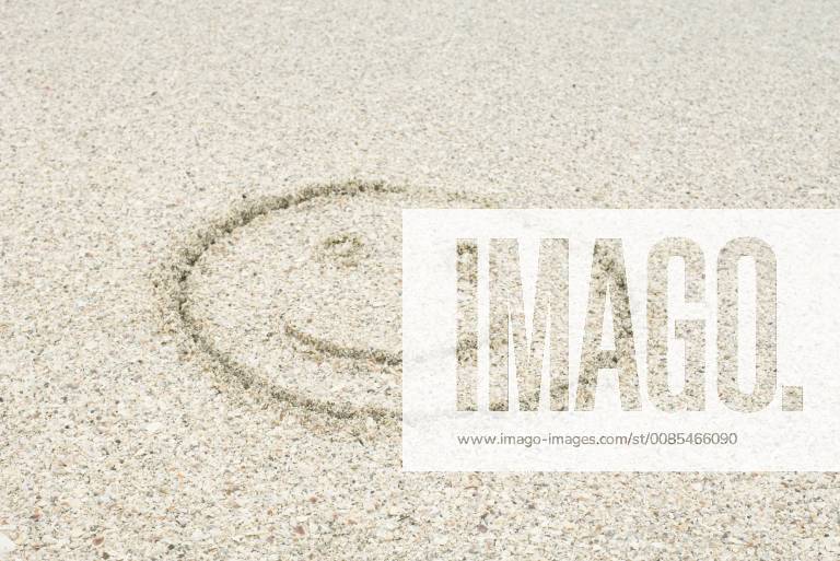 Smiley face drawn in sand at the beach