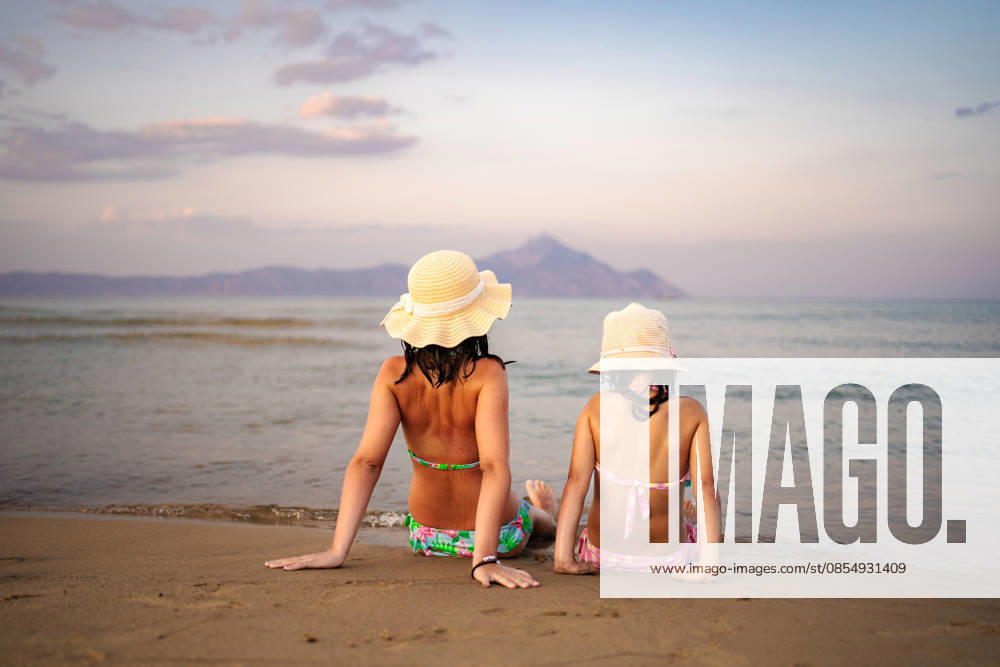 Mutter und Tochter genießen den Sonnenuntergang an einem Strand in Griechenland Mother and daughter sitting on a sandy beach looking at the ocean during sunset (License=RF) ,model released, Symbolfoto