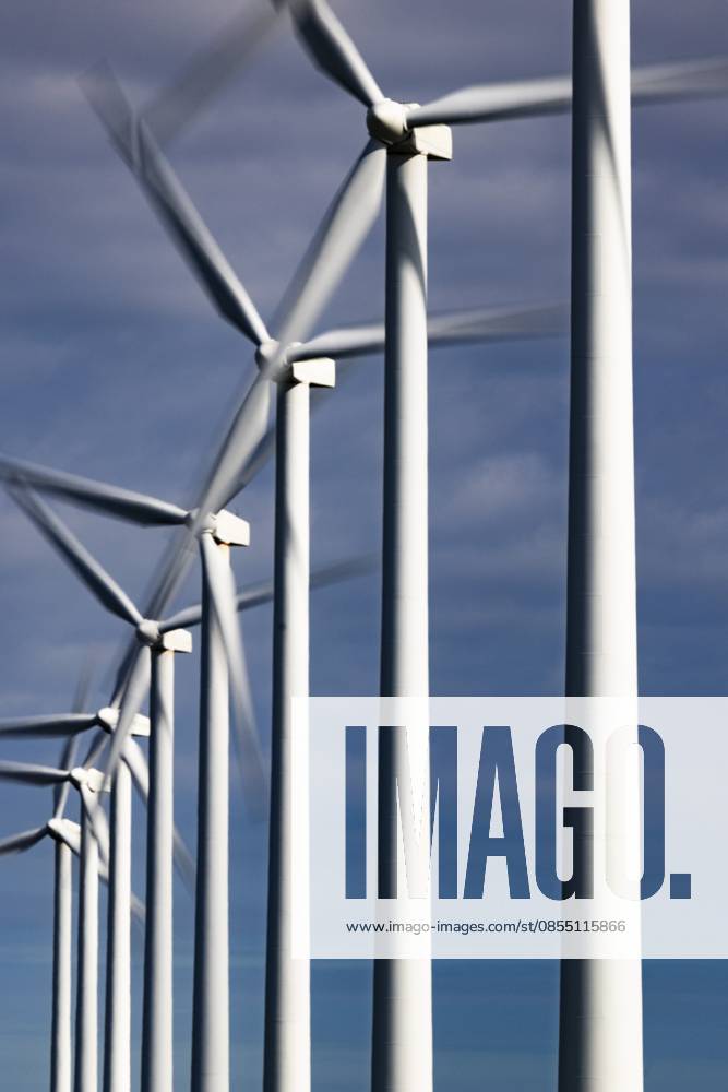 Eine Reihe sich drehender, rotierender Windräder mit Bewegungsunschärfe vor blauem Himmel mit Wolken, Langzeitbelichtung, Windkraft, Windenergie, erneuerbare Energie, Schagen, Nordholland, Niederlande A series of spinning, rotating wind turbines with motion blur against a blue sky with clouds, long exposure, wind power, wind energy, renewable energy, Schagen, North Holland, the Netherlands