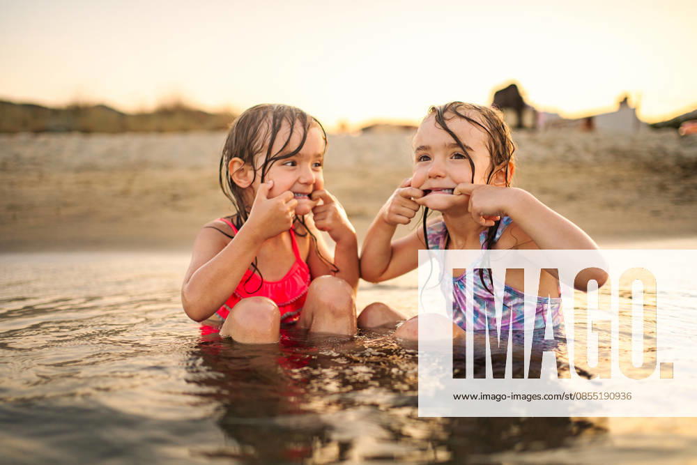 Fröhliche junge Mädchen, die beim Spielen im Wasser am Strand lustige Gesichter schneiden Fröhliche junge Mädchen, die beim Spielen im Wasser am Strand lustige Gesichter schneiden (License=RF) ,model released, Symbolfoto