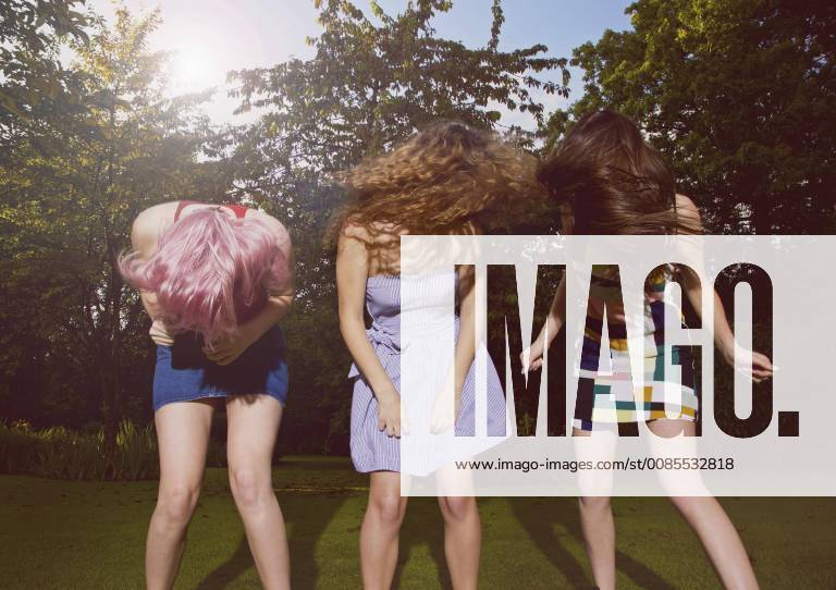 Excited female friends tossing hair at yard during sunny day