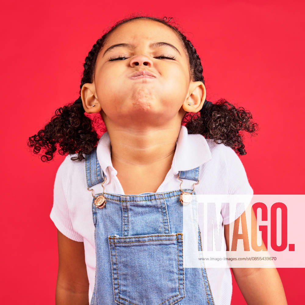 Attitude, childhood and face of girl on red background in studio with angry, upset and frustrated reaction. Emoji, comic and young kid with air in cheeks, tantrum behaviour and mad facial expression. (License=RF) ,model released, Symbolfoto