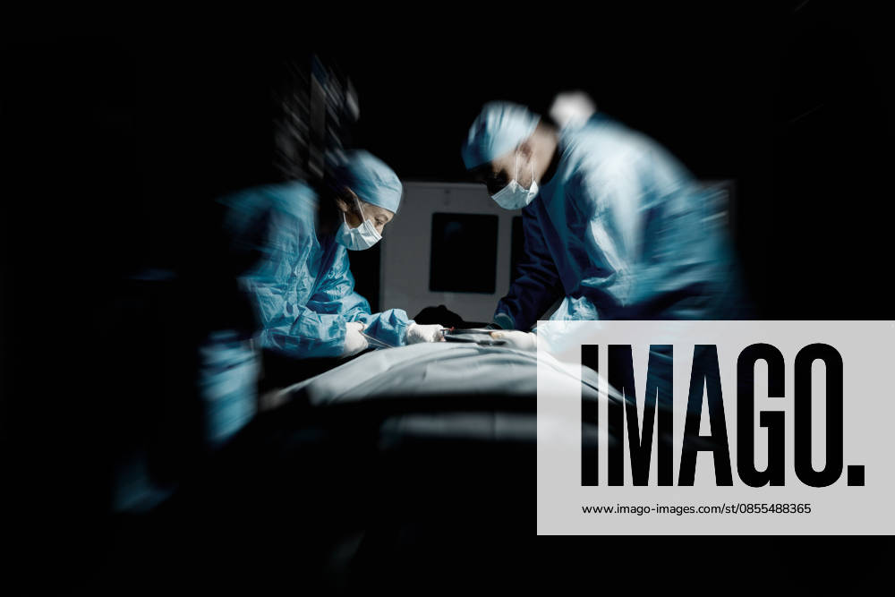 Doctors, night surgery and hospital theater with patient and surgeon team for emergency, teamwork and trust. Medical man and woman in dark for life saving, healthcare and health insurance emergency. (License=RF) ,model released, Symbolfoto