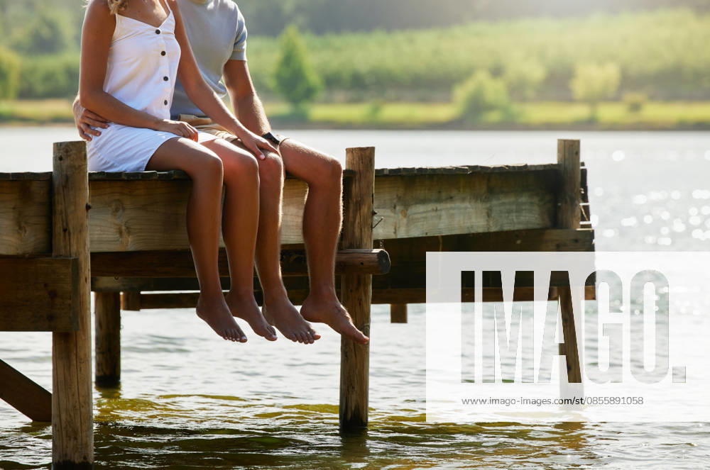 Couple together in nature, relax by lake and summer, travel and adventure, love and care outdoor. People in relationship, trust and bonding on vacation, man and woman sitting on jetty with freedom. (License=RF) ,model released, Symbolfoto