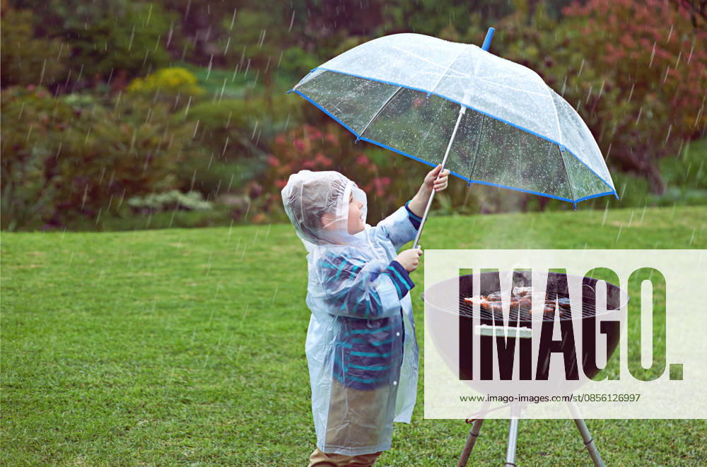 Weather, nature and boy with a grill, rain and wellness with safety, cover and winter outfit. Bbq, male child or kid with umbrella, cold or young person with food, raincoat or outdoor with protection. (License=RF) ,model released, Symbolfoto