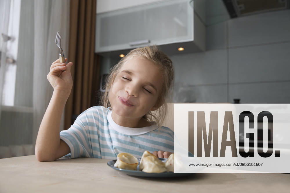 IMAGO Creative, Food, Dumplings Ein achtjähriges Mädchen genießt es, zu Hause in der Küche zum Mittagessen Knödel zu essen An eight-year-old girl enjoys eating dumplings for lunch at home in the kitchen (License=RF) ,model released, Symbolfoto