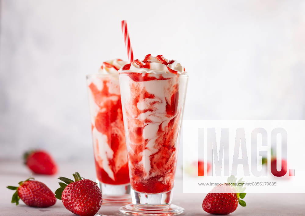 Erdbeermilchshake mit Schlagsahne. Strawberry milkshake with whipped cream and berry syrup in the tall glass on light background. (License=RF)