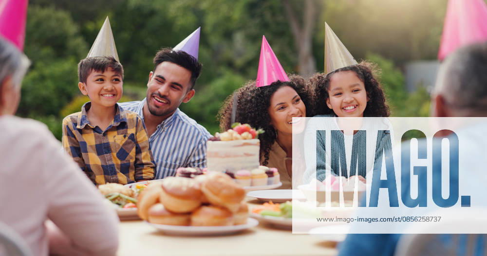 Parents, children and happy with birthday cake in garden with care, love and bonding with food at family home. Father, mother and kids with hat for party, event and embrace at table with celebration. (License=RF) ,model released, Symbolfoto