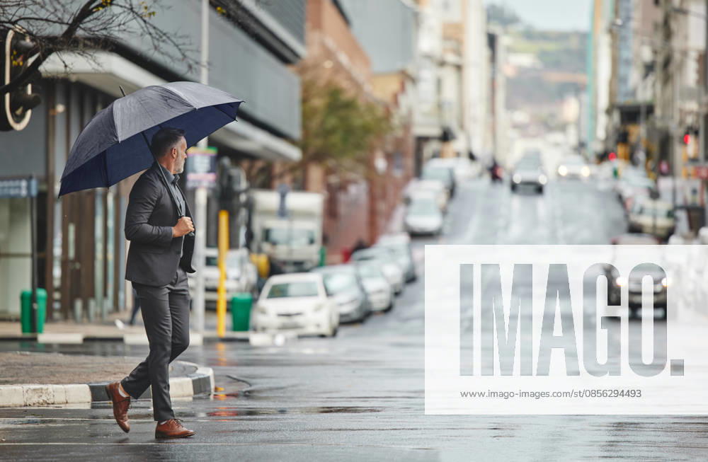 Walking, city and businessman with umbrella for rain in morning commute, travel and journey to office in winter. Professional, corporate and person in urban town for career, job and work in New York. (License=RF) ,model released, Symbolfoto