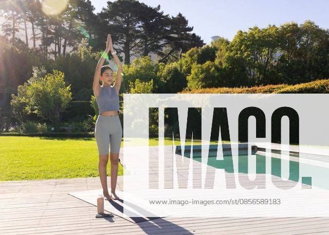 Indian woman practicing yoga in sportswear on wooden deck beside pool with mat, bottle, smartphone, model released, property released, 10.04.2025 06:00:00, 13157950