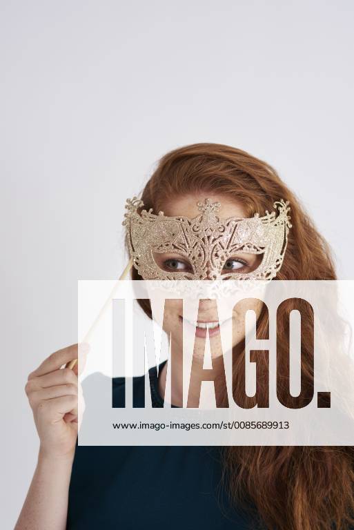Portrait of smiling redheaded woman with masquerade mask model released Symbolfoto ABIF00884