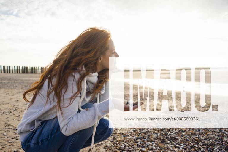 Redheaded woman collecting shell on the beach model released Symbolfoto KNSF04273