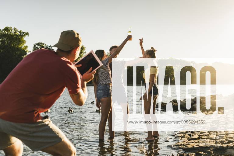 Group of happy friends with tablet in a river at sunset model released Symbolfoto UUF14814