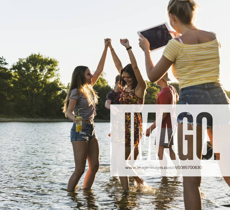 Group of happy friends with tablet in a river at sunset model released Symbolfoto UUF14822