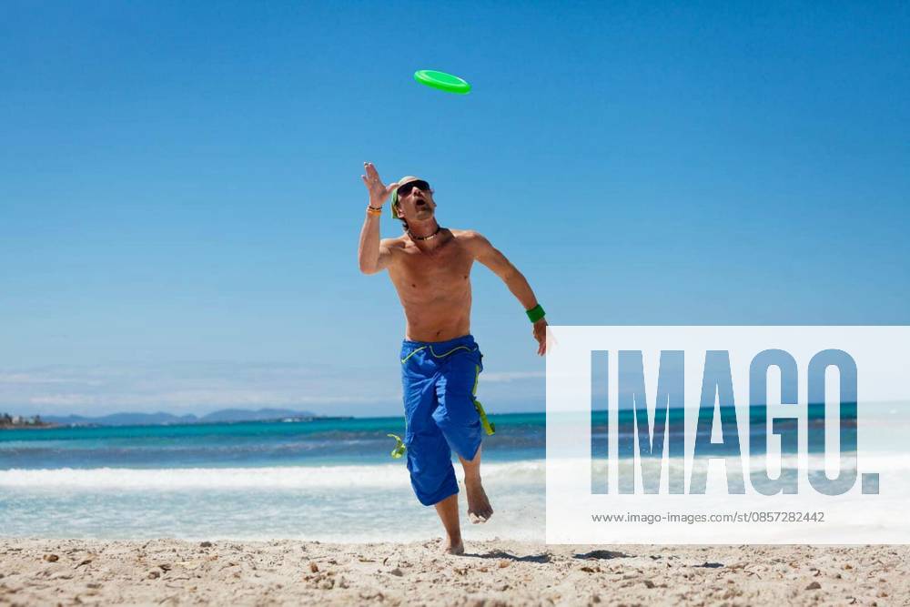 Young adult sporty man plays Frisby Frisbee in summer on beach holiday model released Symbolfoto