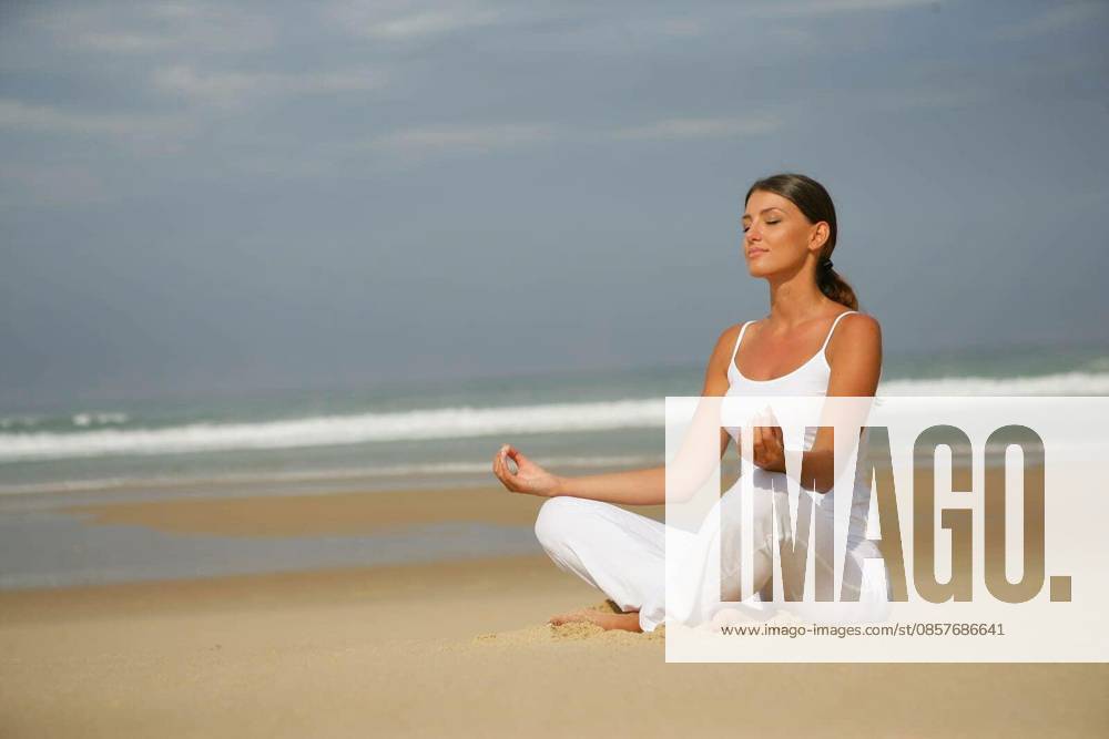 Portrait of a woman meditating by closing the eyes sitting at the seaside model released Symbolfoto