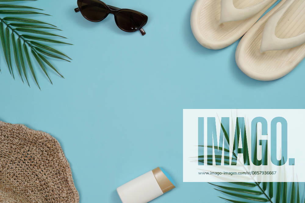 Sommerurlaub-Flatlay mit Sonnenbrille, Flip-Flops und Palmblättern A vibrant flat lay of summer vacation items including sunglasses, flip flops, and palm leaves on a light blue background. (License=RF)