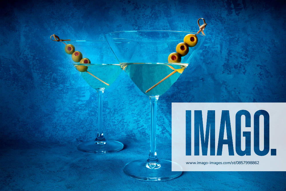 Martini. Zwei Gläser Dirty Martini mit Wermut und Oliven Martini. Two glasses of dirty martini cocktails with vermouth and olives, aperitif, on a blue background, side view (License=RF)