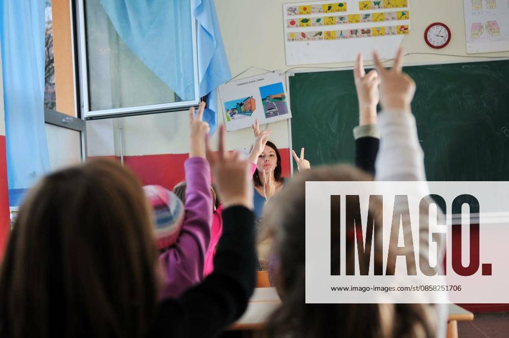 Happy young teacher woman at elementrary school teaching and giving leassons to group of young smart children model released Symbolfoto
