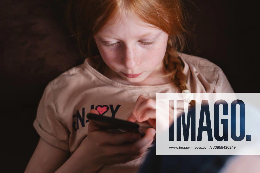 Child looking at smartphone experiencing screen addiction indoors model released, Symbolfoto property released, IHF02737